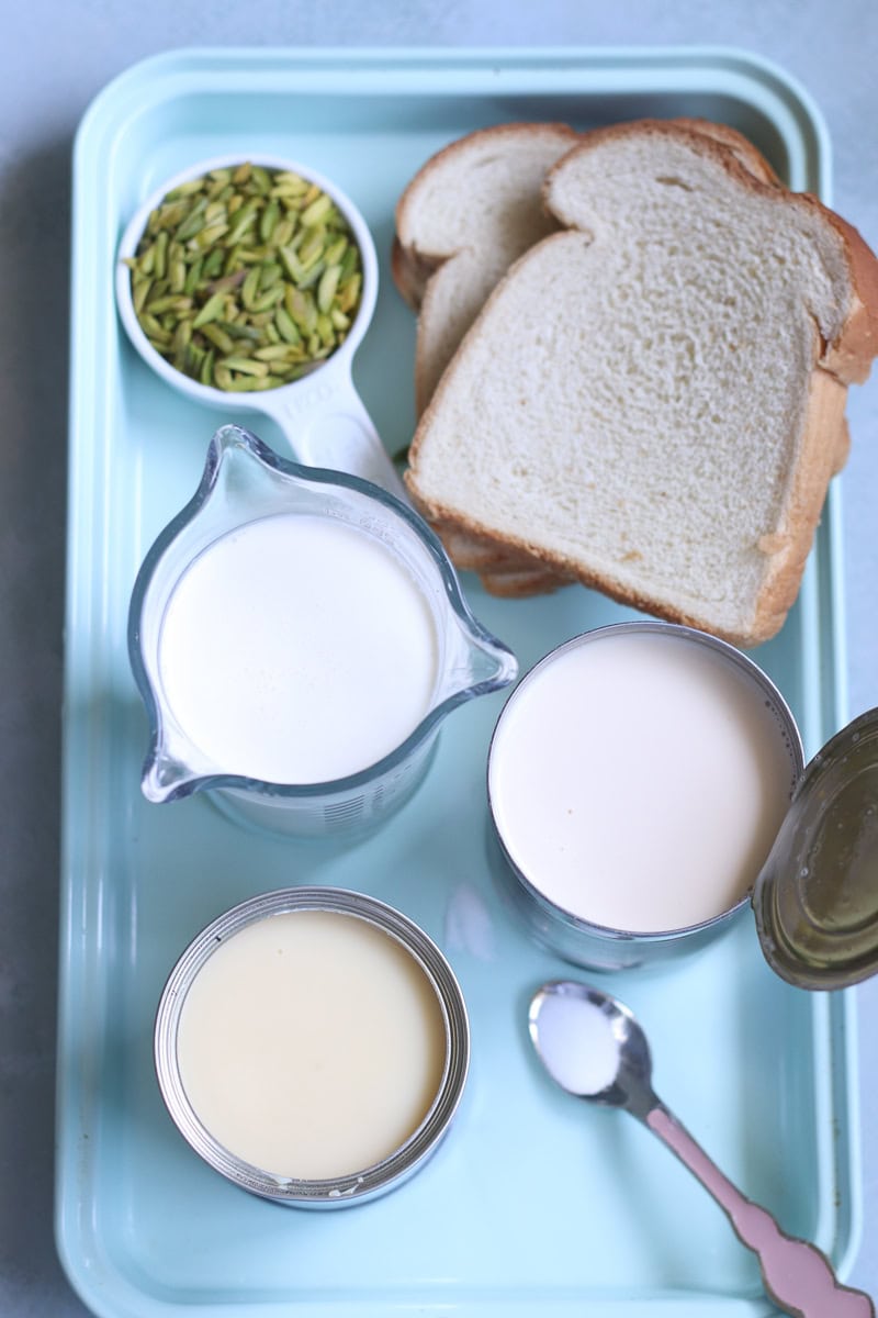 ingredients for pista kulfi on a tray: the three liquids, salt, bread, pistachios. 