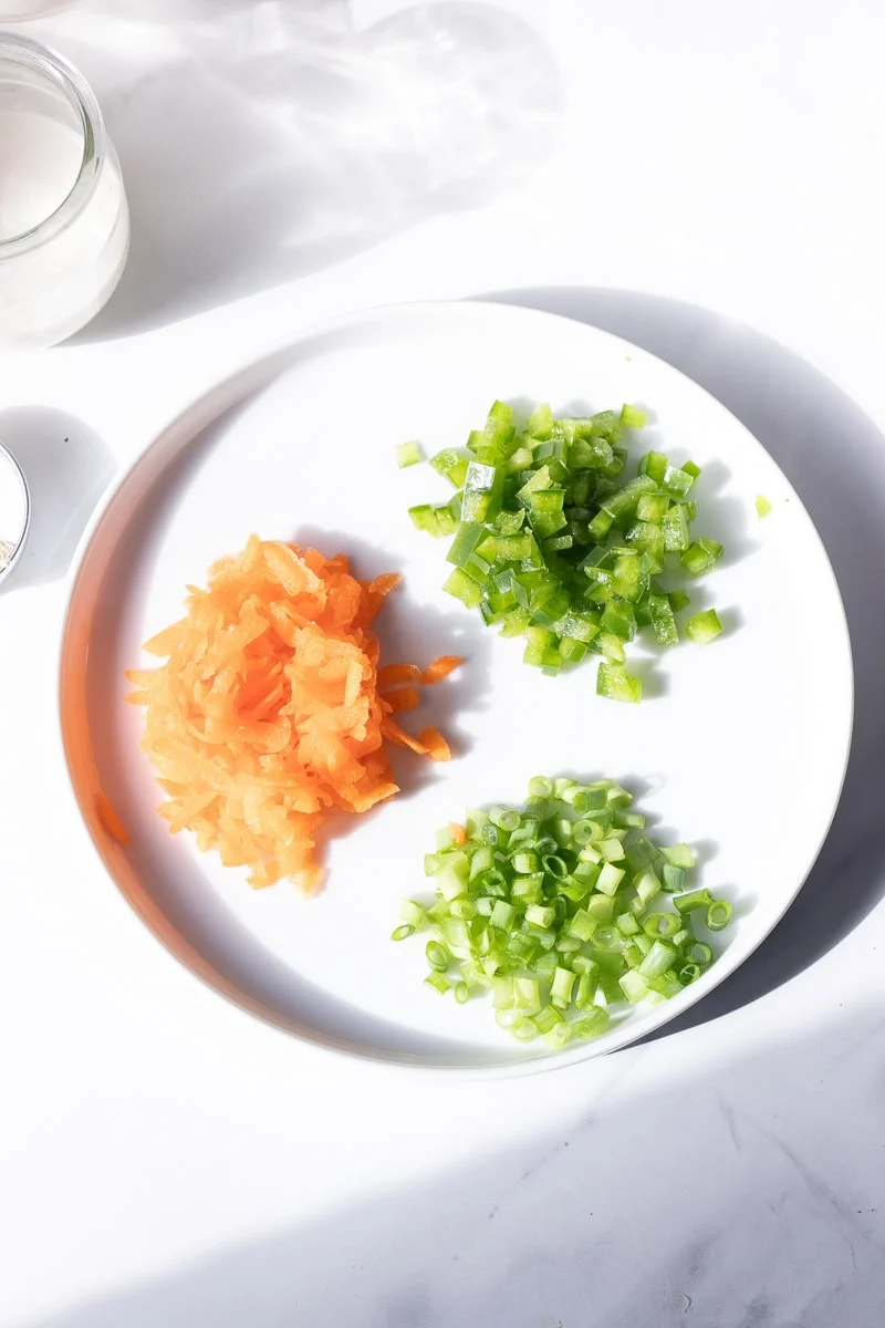 top down view of veggies to add in - diced peppers, shredded carrot and sliced green onions