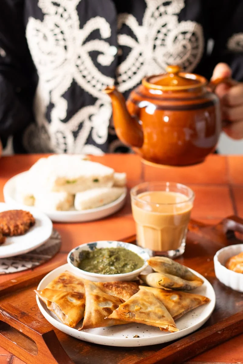  table set for tea with keema samosas, sandwiches and shami kabab