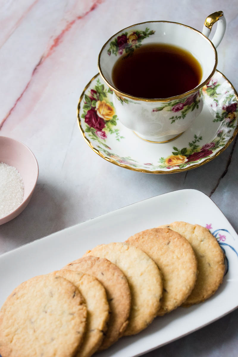 A cup of black tea with a side of jeera biscuits 