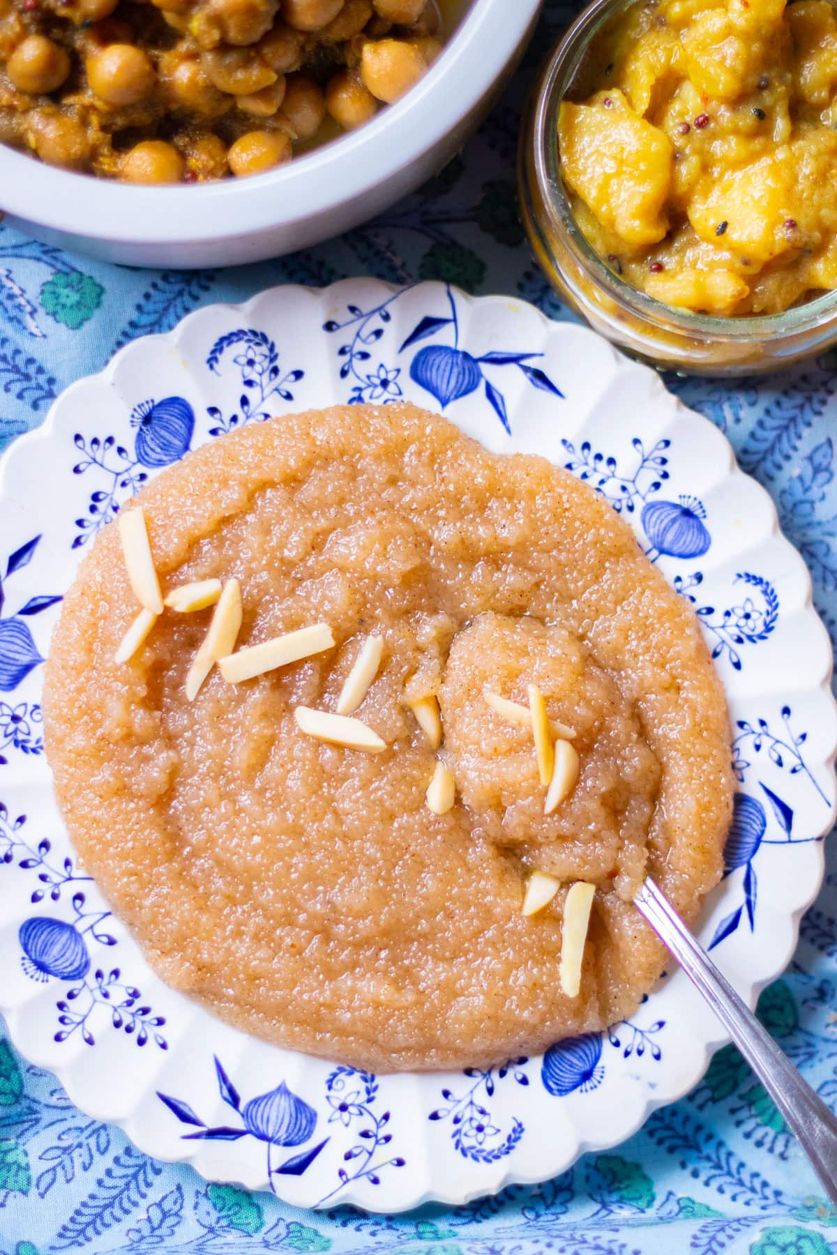 sooji ka halwa in  a plate with chana and aloo in separate dishes 