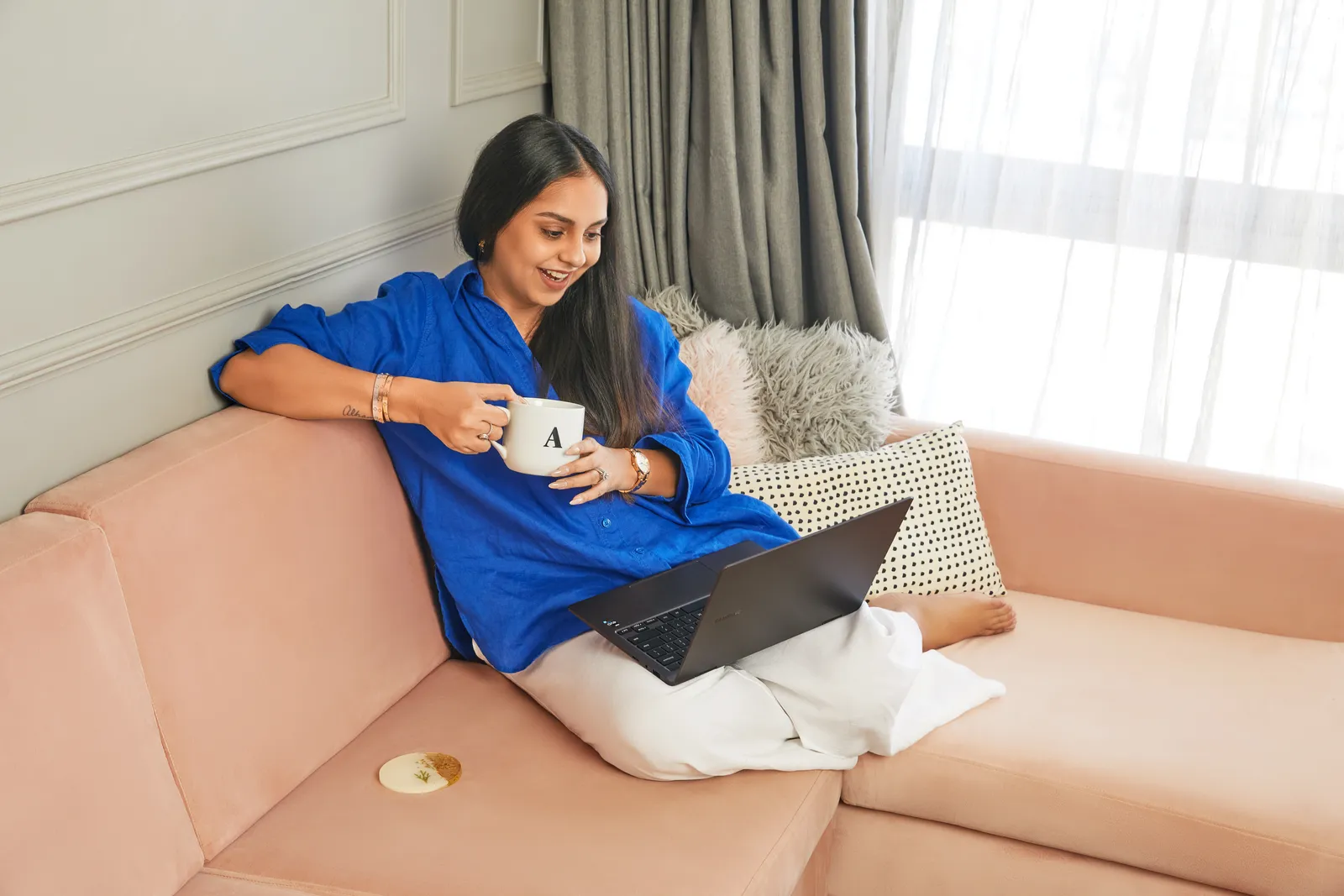 Image may contain Cup Person Sitting Adult Computer Electronics Laptop Pc Couch Furniture and Wristwatch