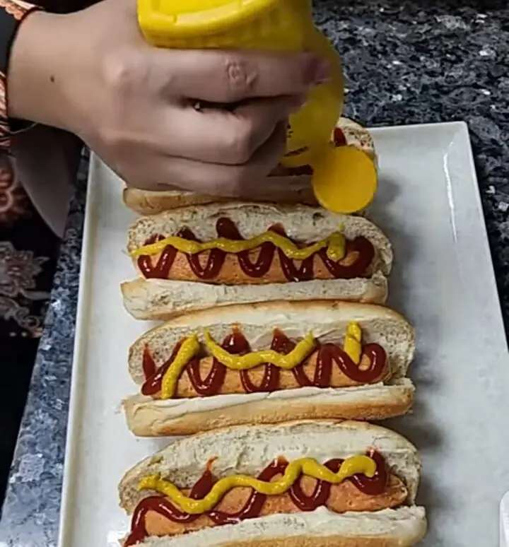 A hot dog is a cooked sausage served inside a partially sliced bread roll or bun, usually topped with ketchup and mustard